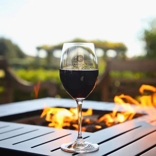 a wine glass outdoors sitting by a fire