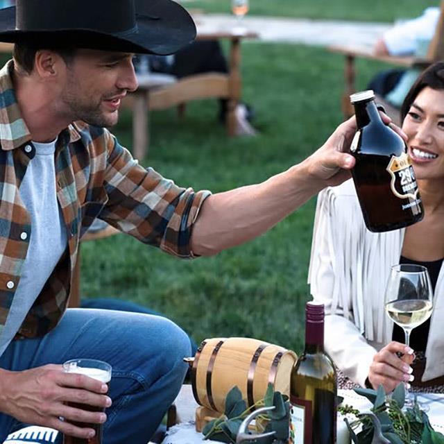 a man in a cowboy hat holding a pint of beer